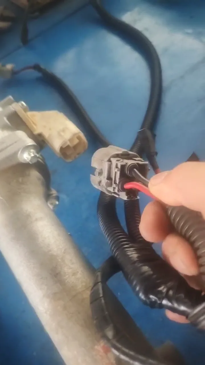 Conector gris de dos vías con dos cables junto a una cremallera de dirección